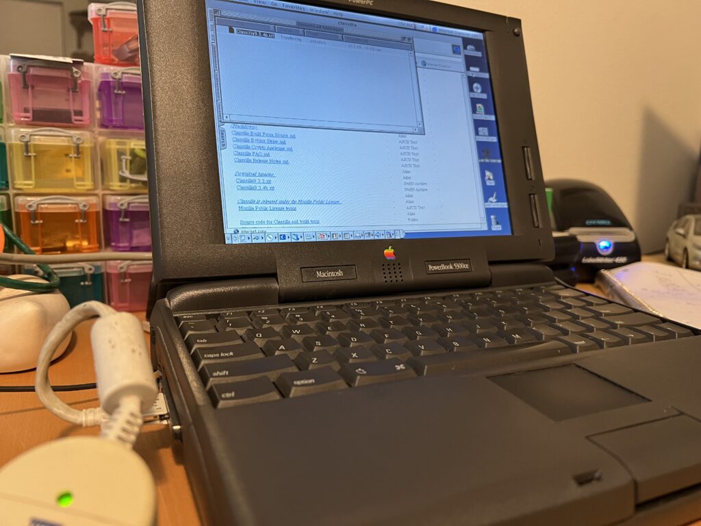 A vintage Powerbook 5300 CS from 1995 connects to the Internet to download some software, using a period-appropriate Ethernet adaptor. 