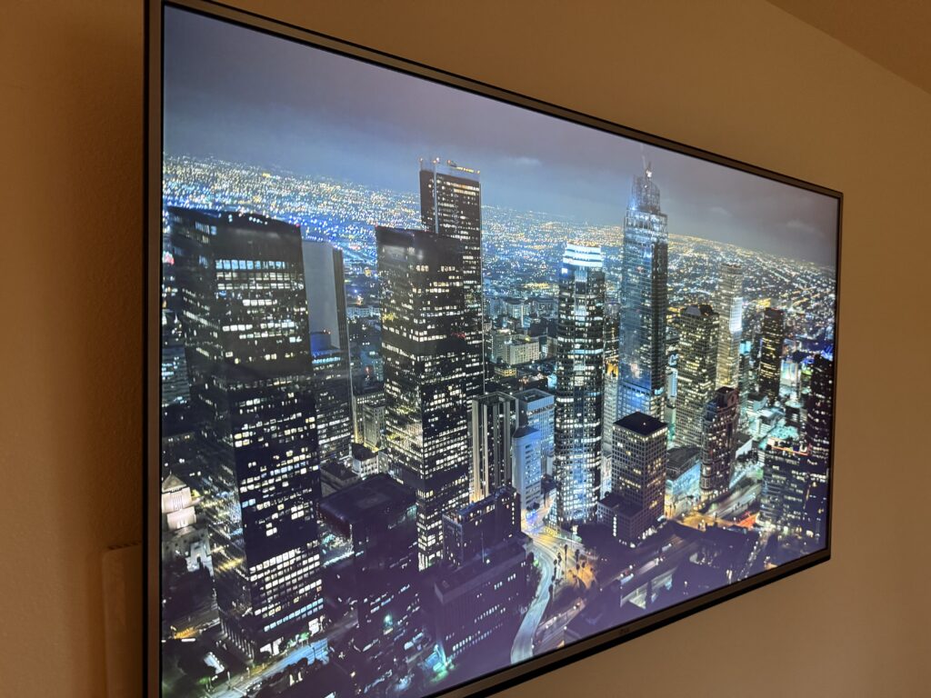 A fixed LG TV showing a night-scape screen saver via an Apple TV